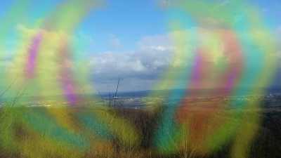 Fotografie einer Landschaft mit bunten Lichtblitzen am Rand zur Darstellung einer Migräne Aura